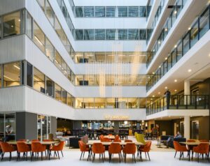 Moderne kantoorlobby aan de Thomas R. Malthusstraat met zithoeken, eetruimte en opvallende verlichtingsinstallatie.